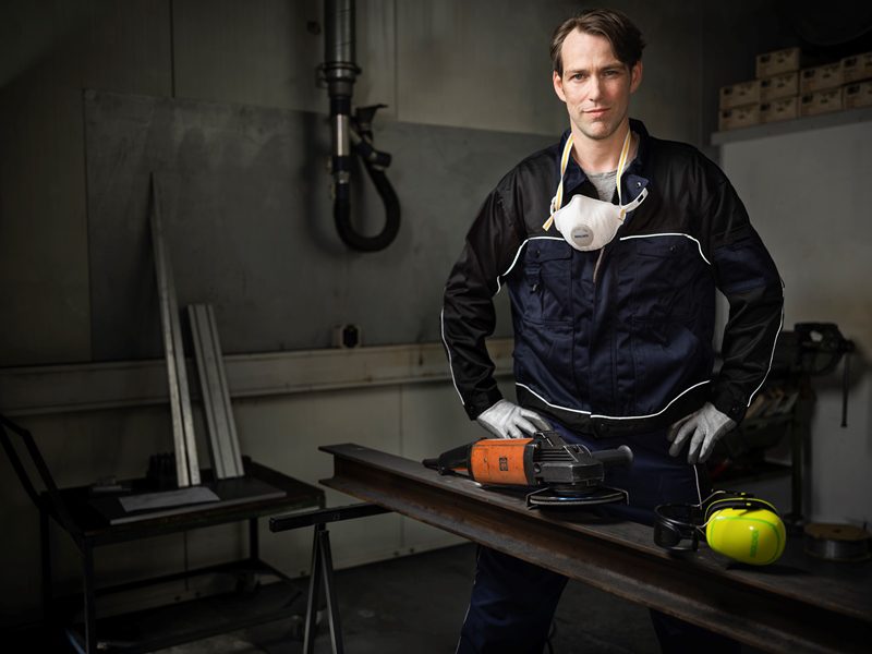 Man with dust mask around his neck and protective gloves on