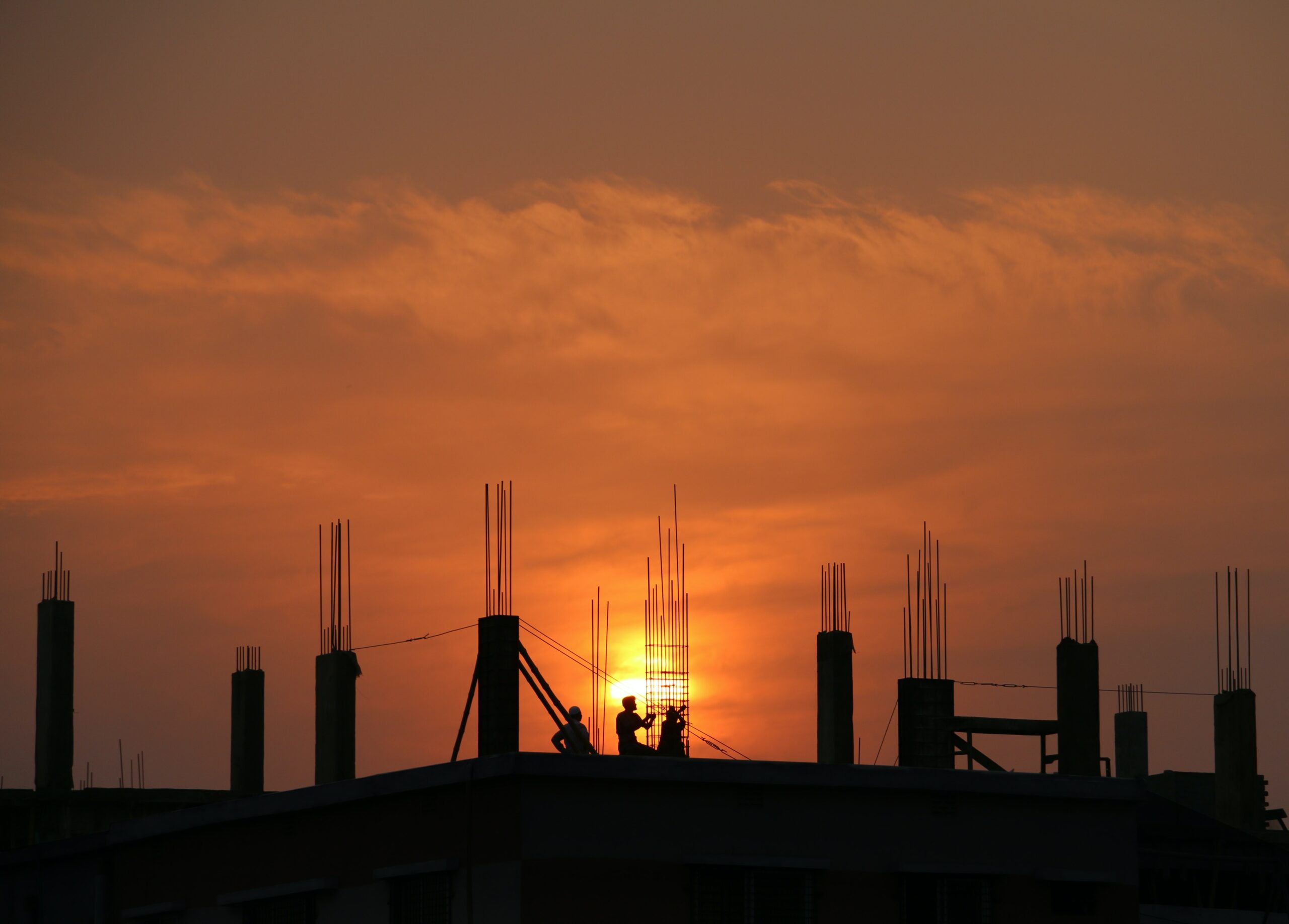 People working on roof with sunset in background